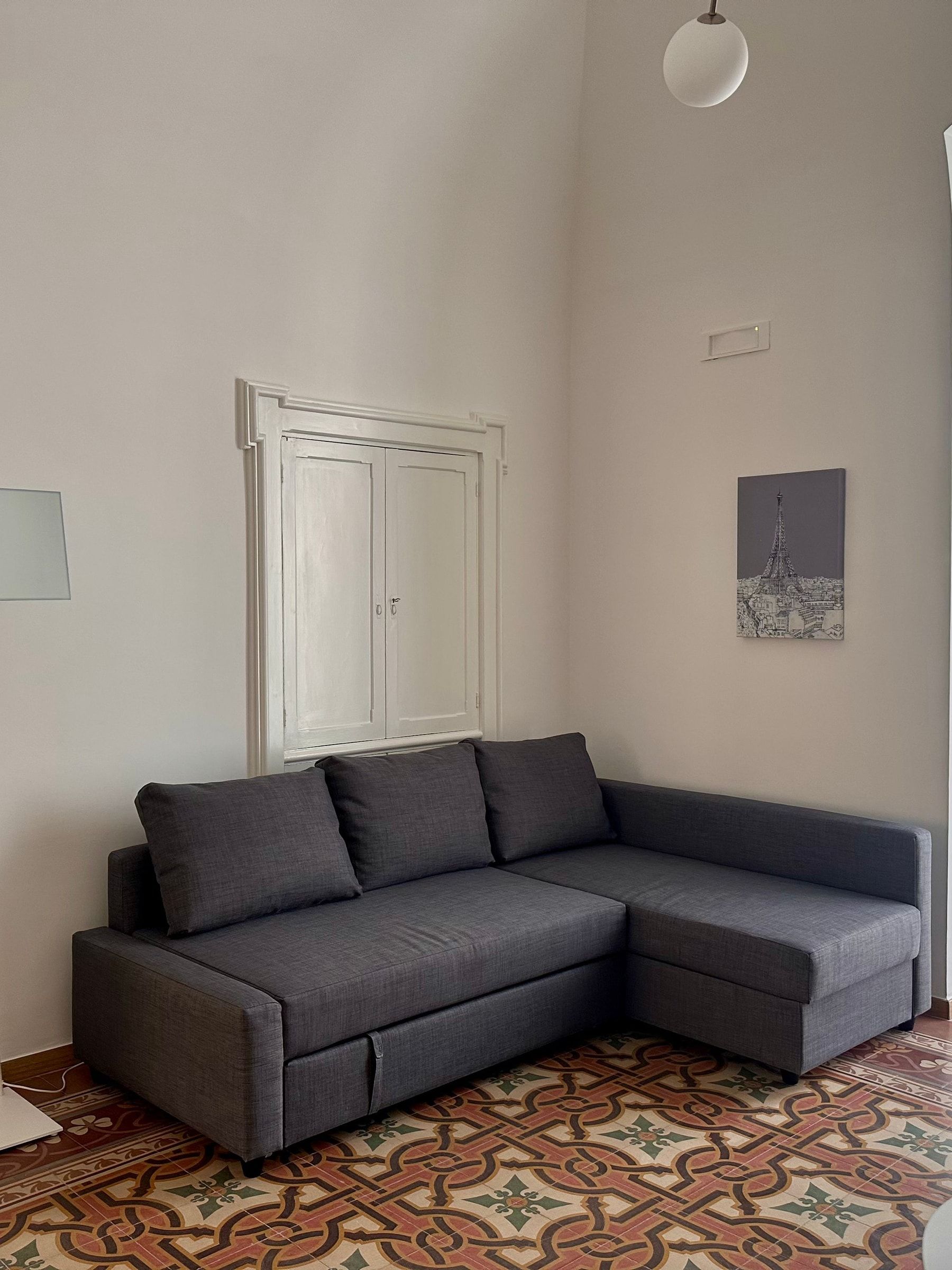Il divano grigio nel soggiorno, davanti all’armadio a muro con la cornice modanata